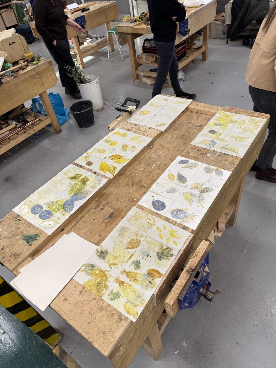 View from above of a workbench with 6 sheets of paper with leaves printed on them.