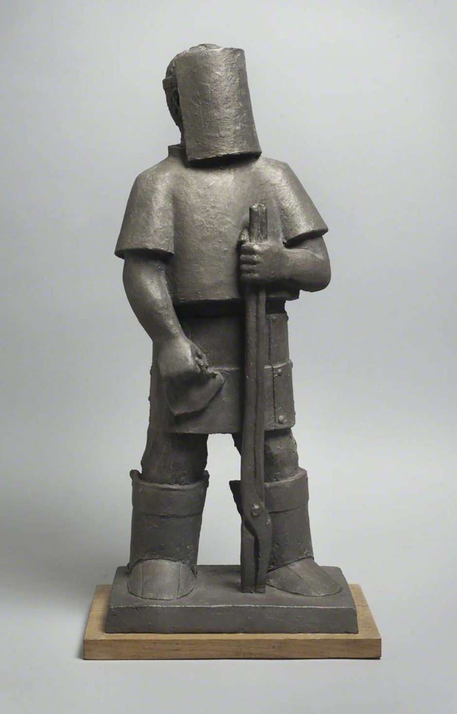 Figurative sculpture of man wearing a visor, he looks to be wearing gear for working in a foundry.