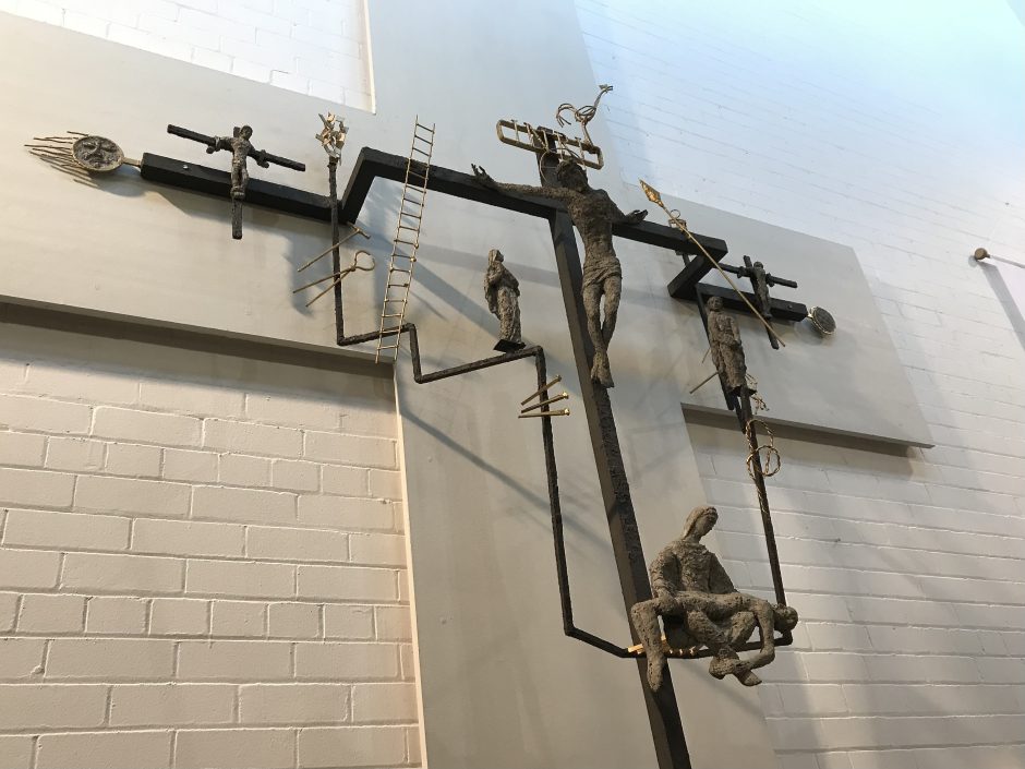 Wall mounted sculpture of crucifix with figurative additions.