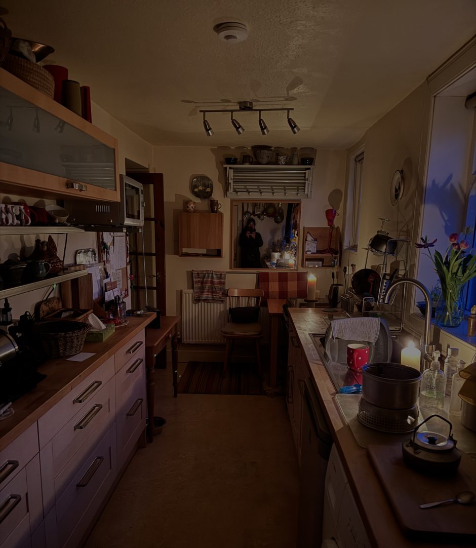 View of the interior of a candle-lit kitchen with a Trangia stove in foreground.