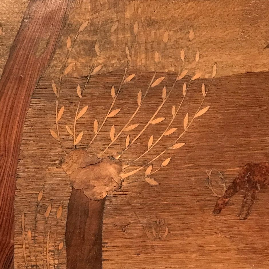 Marquetry of new growth coming from a pollarded tree with a deer to the right.
