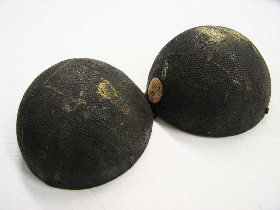 Two hemispheres face down, they are joined together, both are covered with black animal skin which has been put on in irregular patches, there is a circular paper label on one of them which reads 1962 and 18, it also says Edinburgh Museum of Science & Art
