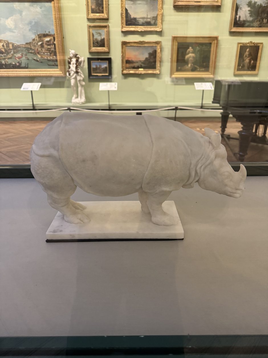 Marble carving of a rhinoceros with paintings in gilded frames in the background