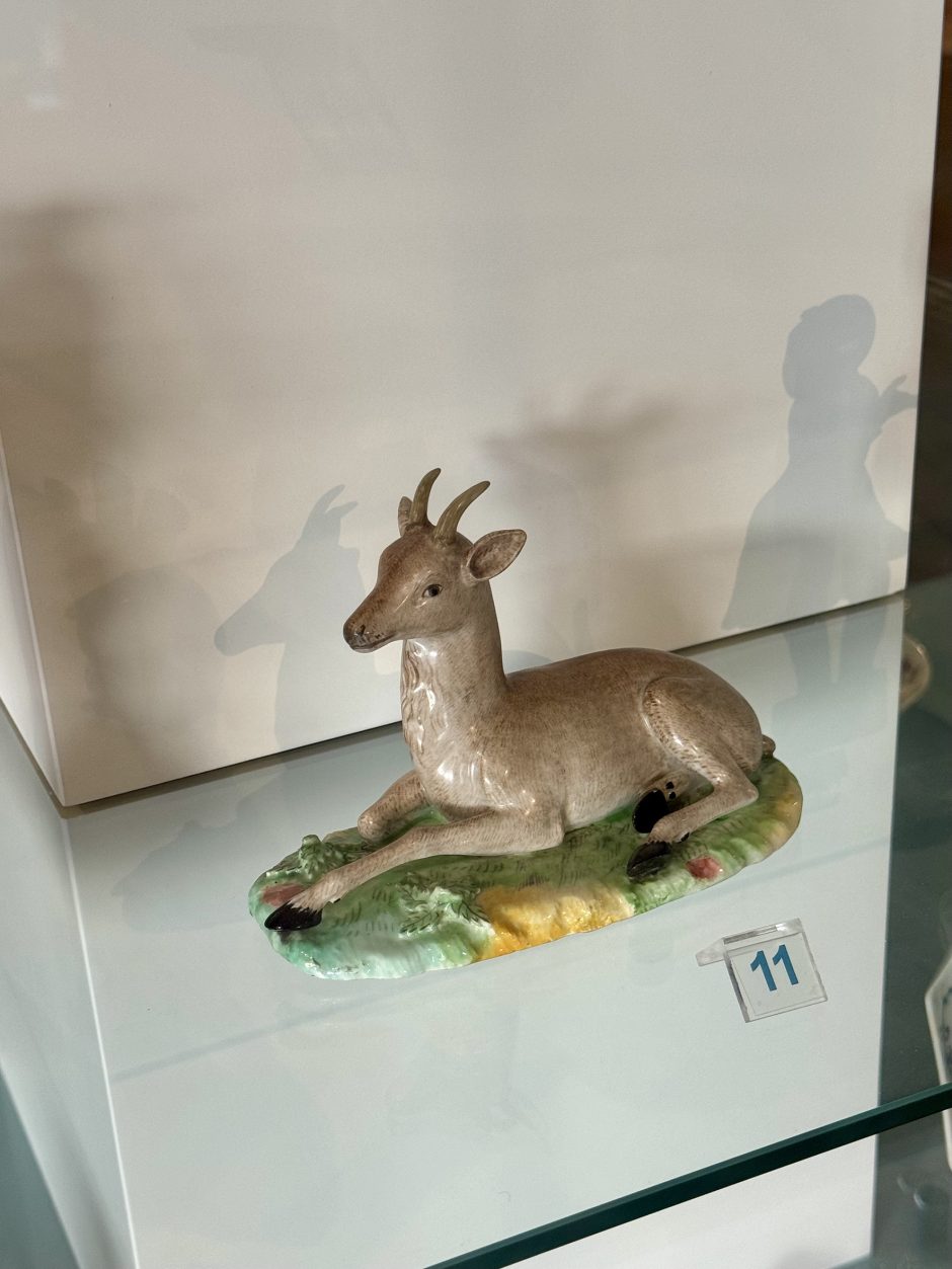 Ceramic deer with coloured glazes, to the right the shadow of a figure from another work in ceramic